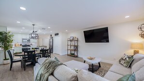 Una sala moderna con un sofá, una mesa de comedor y un televisor montado en la pared.