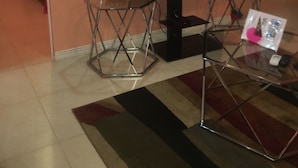 Un salon avec un téléviseur, une table basse en verre et un fauteuil rouge.