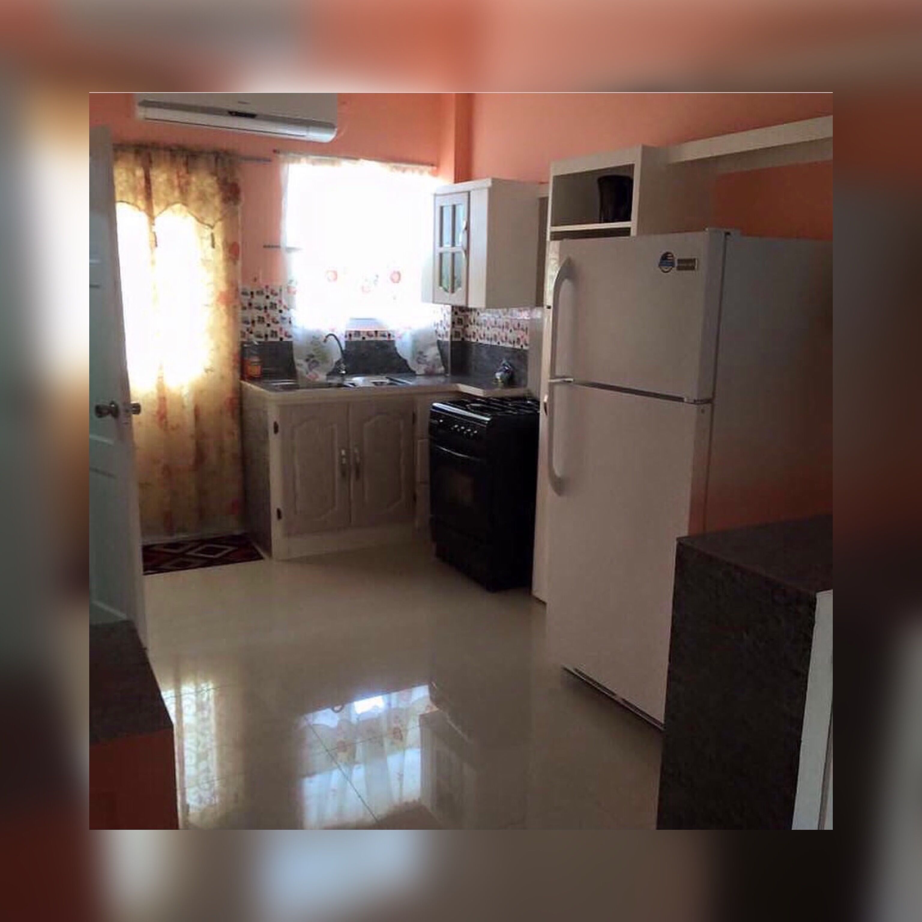 Una cocina compacta con refrigerador, estufa y alacenas.