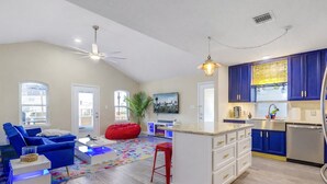 Un salon moderne avec un canapé bleu, un fauteuil en forme de poire rouge et un tapis coloré.