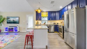 Une cuisine moderne avec des meubles bleus, des appareils en acier inoxydable et un îlot central.