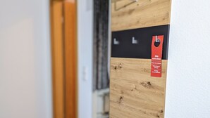 A modern room with a built-in wooden bench, a black cabinet, and a wooden door in the background. - Room in Guest Room - Single Room in City Hotel in the Centre of Rastatt (Rastatt)