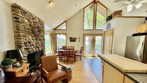 A spacious living area with a stone fireplace, wooden furniture, and a large window. - Greers Ferry Lake Life Dreams (Edgemont)