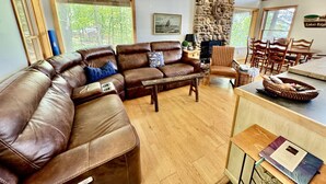 A living room with a brown leather sectional sofa, a wooden coffee table, and a stone accent wall. - Greers Ferry Lake Life Dreams (Edgemont)
