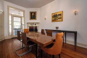 Une salle à manger avec une table en bois, des chaises, une cheminée et des œuvres d’art accrochées au mur.