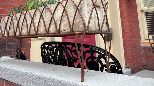 A red brick building with a number '420' above a pink door, a metal planter with daffodils, and a black wrought iron bench. - Victorian on Washington king bed near King St Hot Tub (Alexandria)
