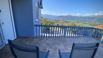 Un balcon avec deux chaises, une vue sur les montagnes et un ciel dégagé.