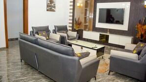 Un salon moderne avec un canapé gris, une table basse et un téléviseur à écran plat fixé au mur.