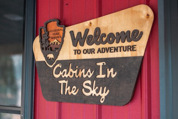 Een houten bord met de tekst 'Welcome to our adventure' en 'Cabins In The Sky'.