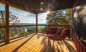 Een houten terras met een hangstoel, met uitzicht op een prachtig landschap.