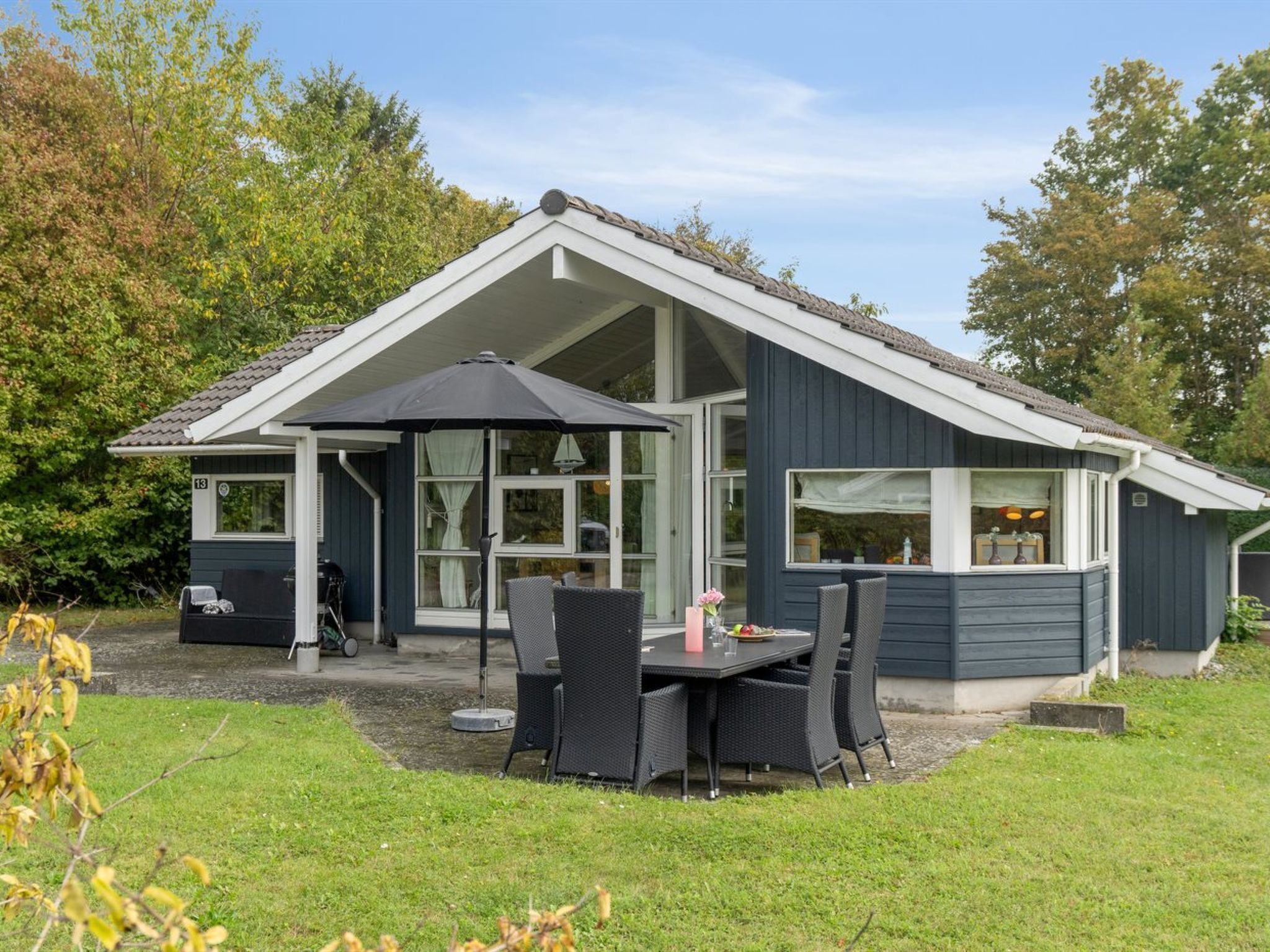 Een modern huis met een overdekte patio, grote ramen en een verzorgd gazon.