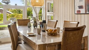A dining area with wicker chairs, a wooden table, a coffee maker, and a vase with flowers. - "Thorke" - 200m from the sea by Interhome (Nysted)