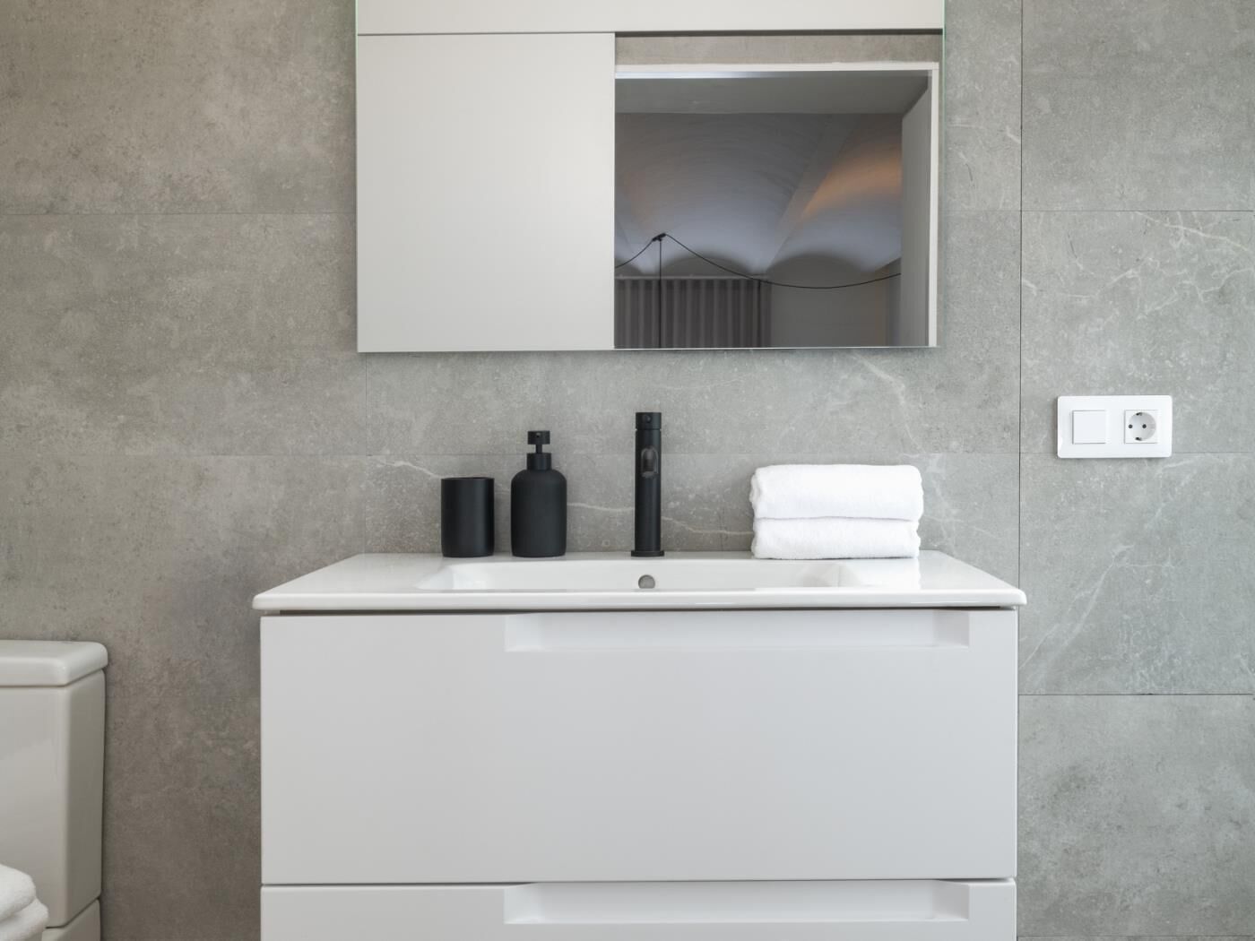 A modern bathroom with a white vanity, a mirror, and a towel.