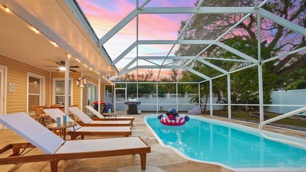 An indoor pool area with lounge chairs, a pool float, and a covered patio. - 4BR Heated Pool|12min to Beach|Gameroom|King beds (Clearwater)