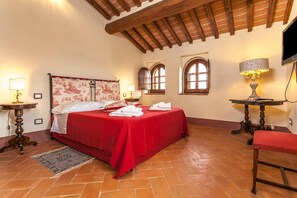 Un dormitorio con cama, dos mesitas de noche, una silla y televisor.