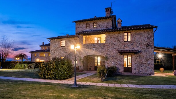 Una casa de piedra con numerosas ventanas y una entrada bien iluminada.