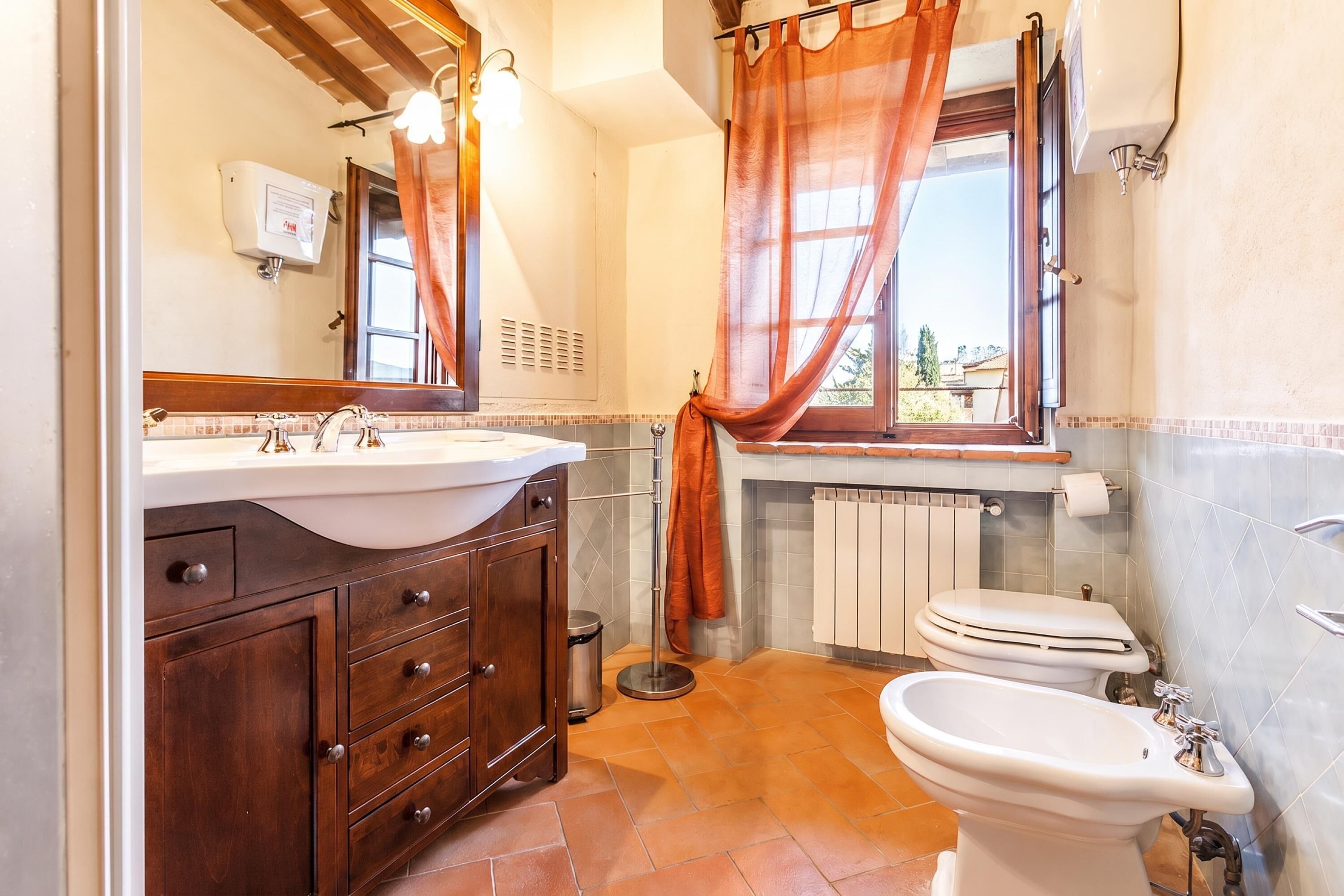 A bathroom with a sink, vanity, toilet, and bidet.