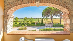 A stone archway leading to a courtyard with a view of a green landscape and trees. - Fratta Orchidee, Cortona, Italy (Cortona)