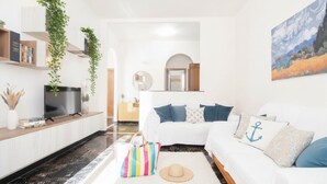 Ein modernes Wohnzimmer mit einem weißen Sofa, einem Flachbildfernseher und einem großen Gemälde an der Wand.