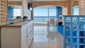 Una habitación con pared de ladrillo, un ventanal amplio, una zona de comedor y un separador de vidrio azul.