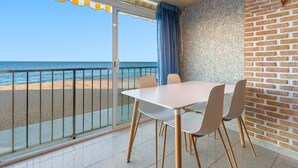 Un comedor con una mesa y sillas, vista a la playa y una pared de ladrillo.