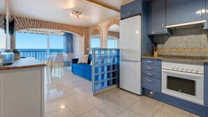 Una cocina moderna con horno empotrado, refrigerador y comedor con vista al mar.