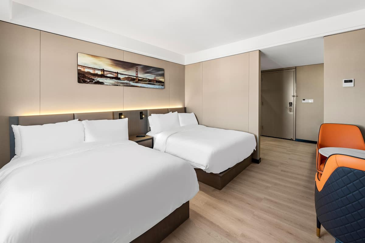 Une chambre d’hôtel avec deux lits, un bureau et une chaise.
