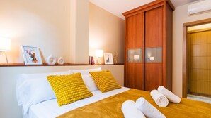 A hotel room with a bed, a wooden wardrobe, and a door.
