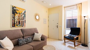 A living room with a brown sofa, patterned pillows, a small round coffee table, a decorative mirror, and a framed picture on the wall.