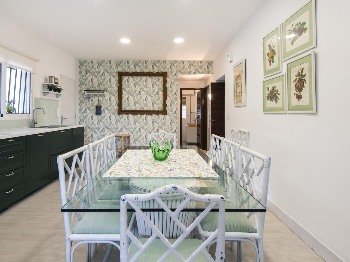 A modern kitchen with dark cabinets, a glass dining table, and white chairs.