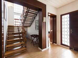 A wooden staircase leading to a second floor, a door with a geometric glass pattern, and a small wooden table. - Queen of the ocean Villa: stately style house with pool (MALAGA)