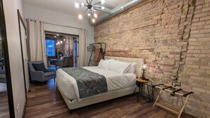 Quarto com uma cama grande, parede de tijolos e piso de madeira.
