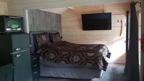 Une chambre à coucher comprenant un lit, un téléviseur, une armoire et un extincteur.