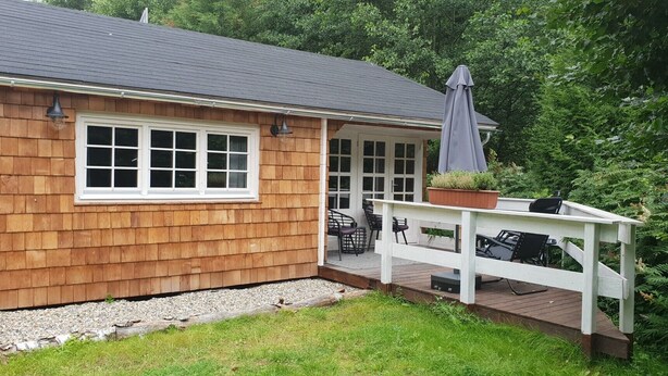 Une maison en bois avec un porche, une fenêtre et une plante en pot.