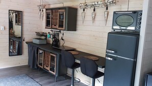 Une cuisine compacte équipée d’un réfrigérateur, de tabourets de bar et d’une petite table à manger.