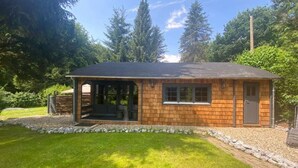 A small wooden cabin with a porch, surrounded by a grassy yard and trees. - Tiny house 'Weißenthalsmühle Eichenhäuschen' with Private Terrace (Niedenstein OT Kirchberg)
