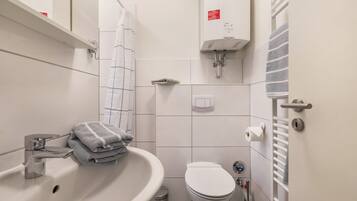 Ein Badezimmer mit Waschbecken, Toilette, Handtuchhalter und einem Handtuch.