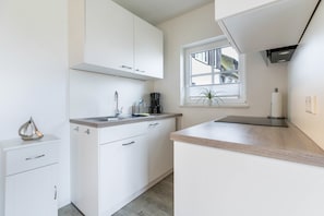 A modern kitchen with white cabinetry, a window with a view, and a countertop with a coffee maker.
