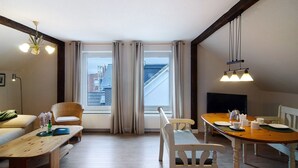 A dining area with a wooden table, chairs, and a view of buildings through large windows.