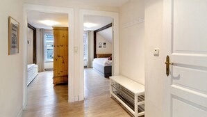 A hallway with a bed, a wooden wardrobe, and a white bench.