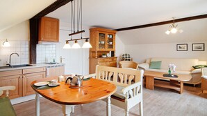 A kitchen with wooden cabinets, a dining table, and a white sofa in a living area.