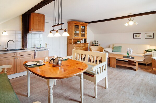 A kitchen with wooden cabinets, a dining table, and a white sofa in a living area.