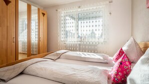 Ein Schlafzimmer mit Bett, Kleiderschrank und einem Fenster mit Blick.