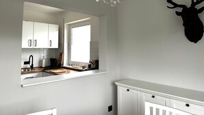 A modern kitchen with white cabinets, a wooden countertop, and a large window.