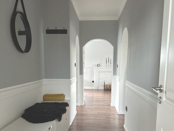 A hallway with a bench, a fireplace, and an archway leading to a room.