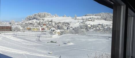 Eine verschneite Landschaft mit Blick auf eine Stadt und Häuser in der Ferne.