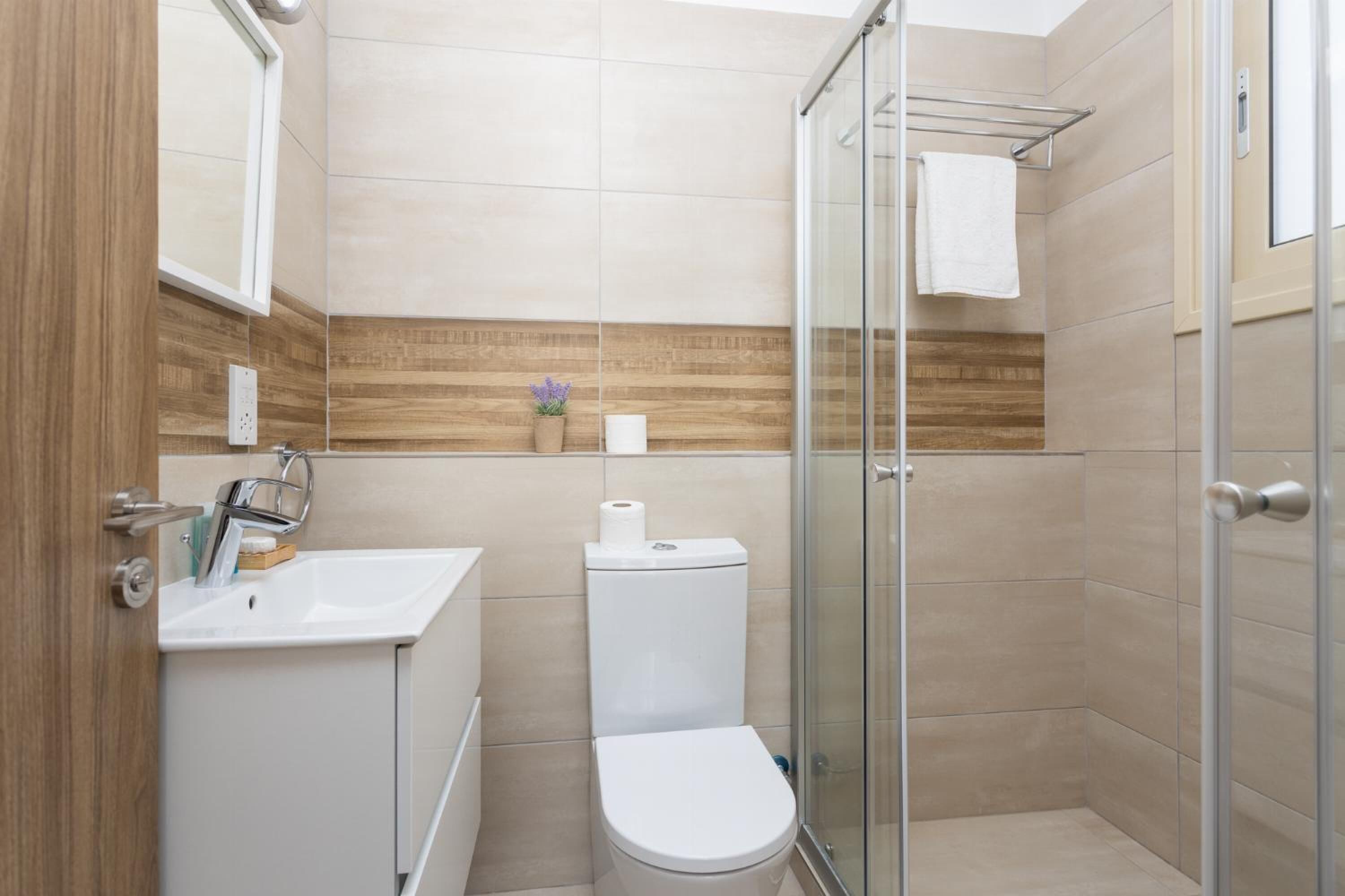 Une salle de bain moderne avec une douche à l’italienne en verre, un lavabo blanc et des toilettes.