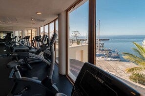 A gym with treadmills and exercise equipment, large windows with a marina view.