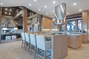 A modern kitchen with a central island, bar stools, and a stone accent wall.