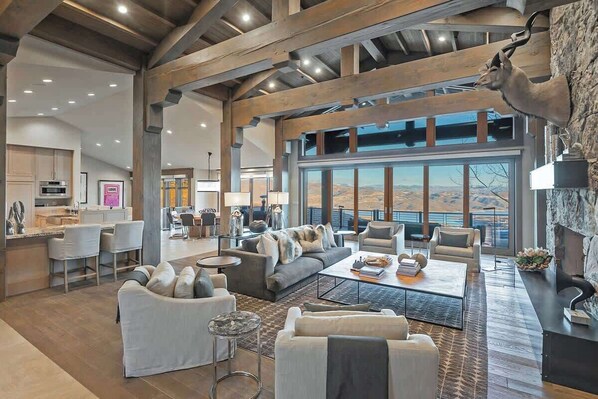 A spacious living area with a large sofa, coffee table, and fireplace. There is a kitchen area with modern appliances and a dining space.